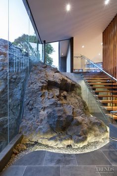 a large rock sitting in the middle of a room next to a stair case with glass railings