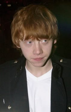 a young man wearing a black jacket and white t - shirt is looking at the camera