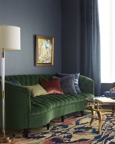 a living room with a green couch and colorful rugs on the floor in front of a blue wall