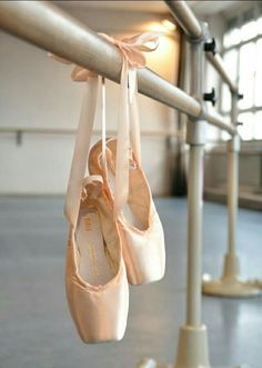 several ballet shoes hanging from a rail in a dance studio