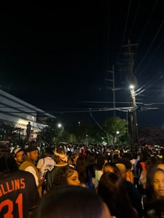 a large group of people standing around each other in front of a building at night