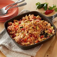 a pan filled with rice and vegetables on top of a wooden table