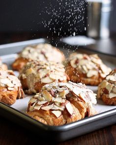 baked goods are sprinkled with almonds on a baking sheet