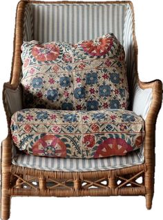 a wicker chair with blue and red flowers on the back, in front of a white background