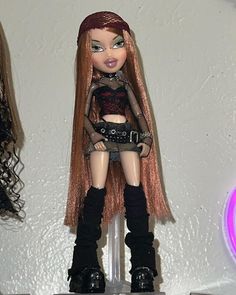 there is a doll with long red hair and black boots on top of a shelf