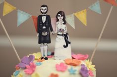 a bride and groom are standing on top of a cake with flags in the background