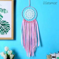 a blue wall with a pink and white dream catcher hanging from it's side