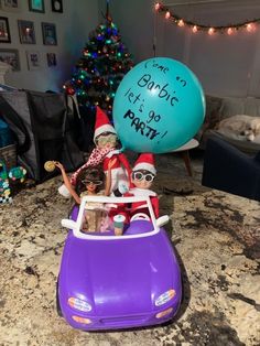 two elfs in a purple car with a blue balloon that says, santa is it's so party