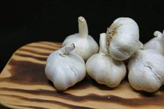 some garlic on a wooden cutting board with one bulb still attached to the top and five heads