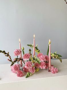 pink carnations and other flowers are arranged in a row on a white surface