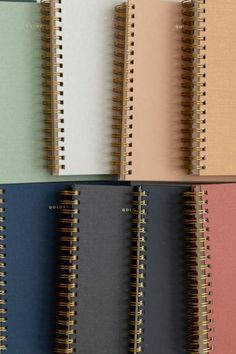 several spiral notebooks lined up in different colors and sizes, each with a blank page