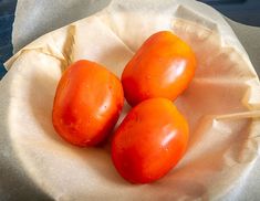 three tomatoes are sitting in a bowl on wax paper