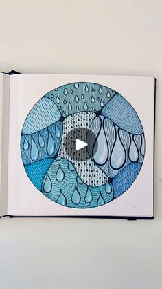 an open book with blue and white designs on the cover, which is surrounded by water drops