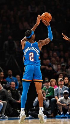 the basketball player is about to dunk the ball in front of his opponent and fans