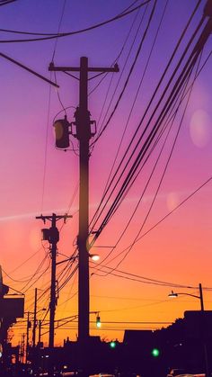 the sun is setting behind power lines and telephone poles with cars driving down the street