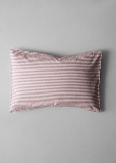 a pink and white striped pillow on a gray wall