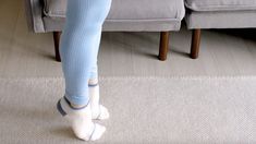 a woman in blue leggings and white shoes standing on the floor with her legs crossed