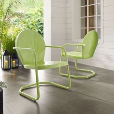 two green chairs sitting next to each other on a patio