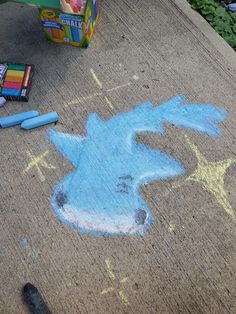 chalk drawing of a blue horse on the ground next to crayons and markers