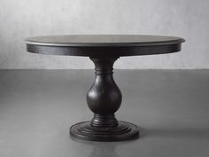 a round wooden table sitting on top of a gray floor