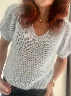 a woman with red hair wearing a white sweater