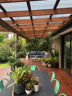 an outdoor patio covered in plants and potted plants on top of a wooden table