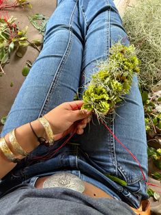 a person laying on the ground with some plants in their lap and one hand holding something