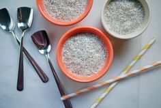 three orange bowls filled with oatmeal next to spoons and utensils