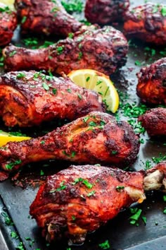 baked chicken wings with lemon wedges and parsley on a baking sheet, ready to be served