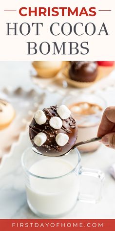 Hot cocoa bomb topped with sprinkles and marshmallows about to be dipped in a mug of hot milk. Text overlay reads "Christmas Hot Cocoa Bombs".