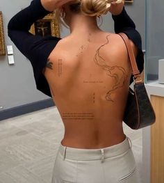 the back of a woman's body with tattoos on it