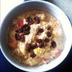 a bowl of oatmeal with raisins and apples