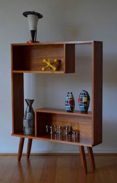 a wooden shelf with two vases on top of it next to a small table