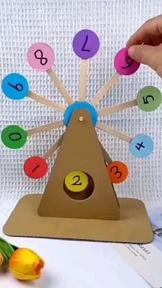 a hand holding a wooden toy with numbers on it