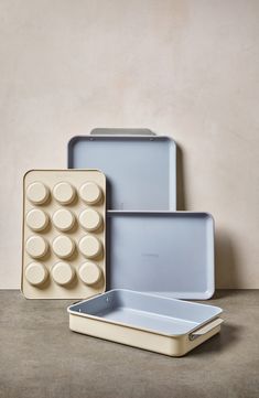 three pans and one tray are sitting on the floor next to each other in front of a wall