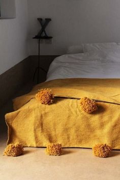 three pom - poms are placed on the edge of a yellow blanketed bed