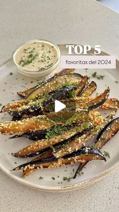 a white plate topped with fried eggplant next to a bowl of ranch dressing