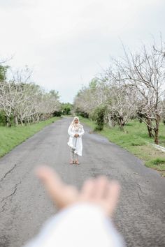 a person standing in the middle of a road with their hand up to the camera