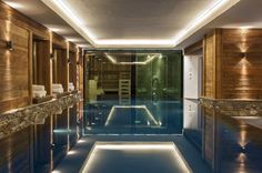 an indoor swimming pool surrounded by wooden walls and flooring with lights on the ceiling