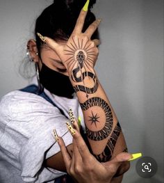 a woman holding her hand up to her face with tattoos on the arm and wrist