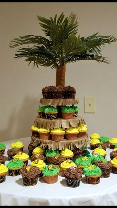 a table topped with lots of cupcakes and a palm tree on top of it