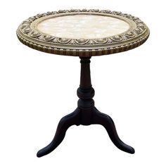 an ornately decorated wooden table with white marble top and black legs, against a white background