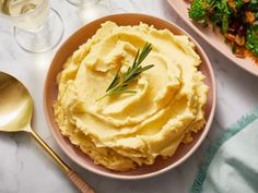 mashed potatoes in a bowl with a sprig of rosemary next to it