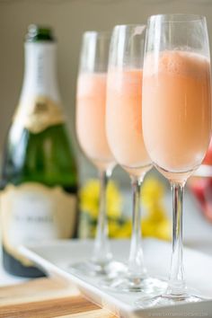 three wine glasses filled with liquid sitting on a tray