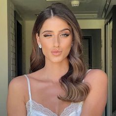 a woman with long brown hair wearing a white bra and earrings is posing for the camera