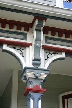 a blue and red clock on the side of a building with white trim around it