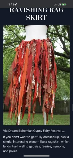 a mannequin with red and orange ribbons hanging from it's torso, in front of a tree