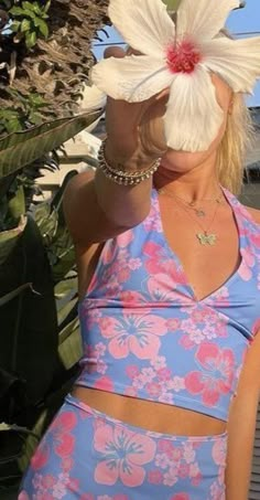 a woman in a blue and pink dress holding a white flower up to her face