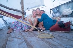 two people are sitting on the deck of a sailboat and posing for a photo