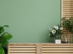 two vases with flowers sit on top of a wooden cabinet